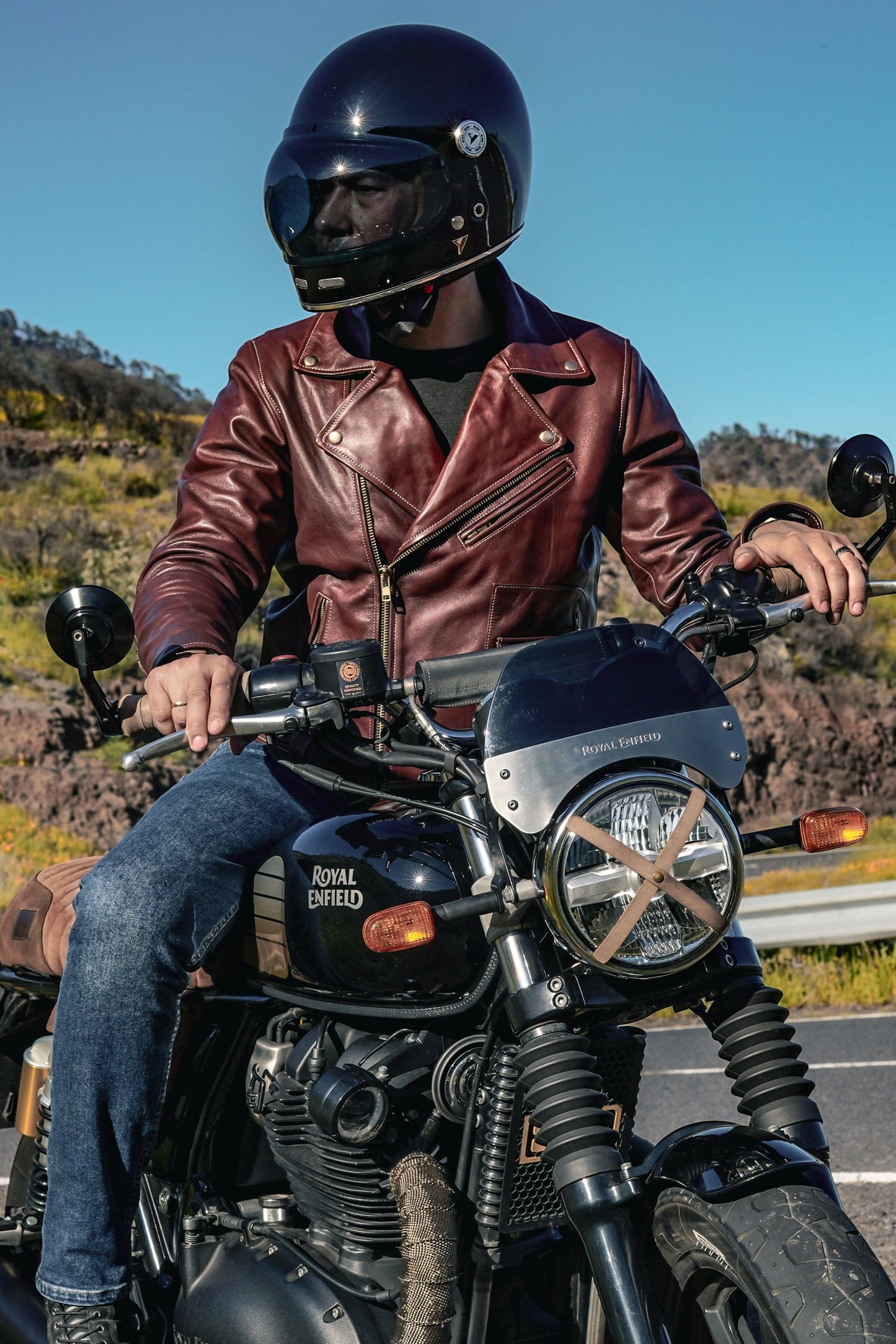 model wearing Rouven maroon leather biker jacket for men on a bike – front view