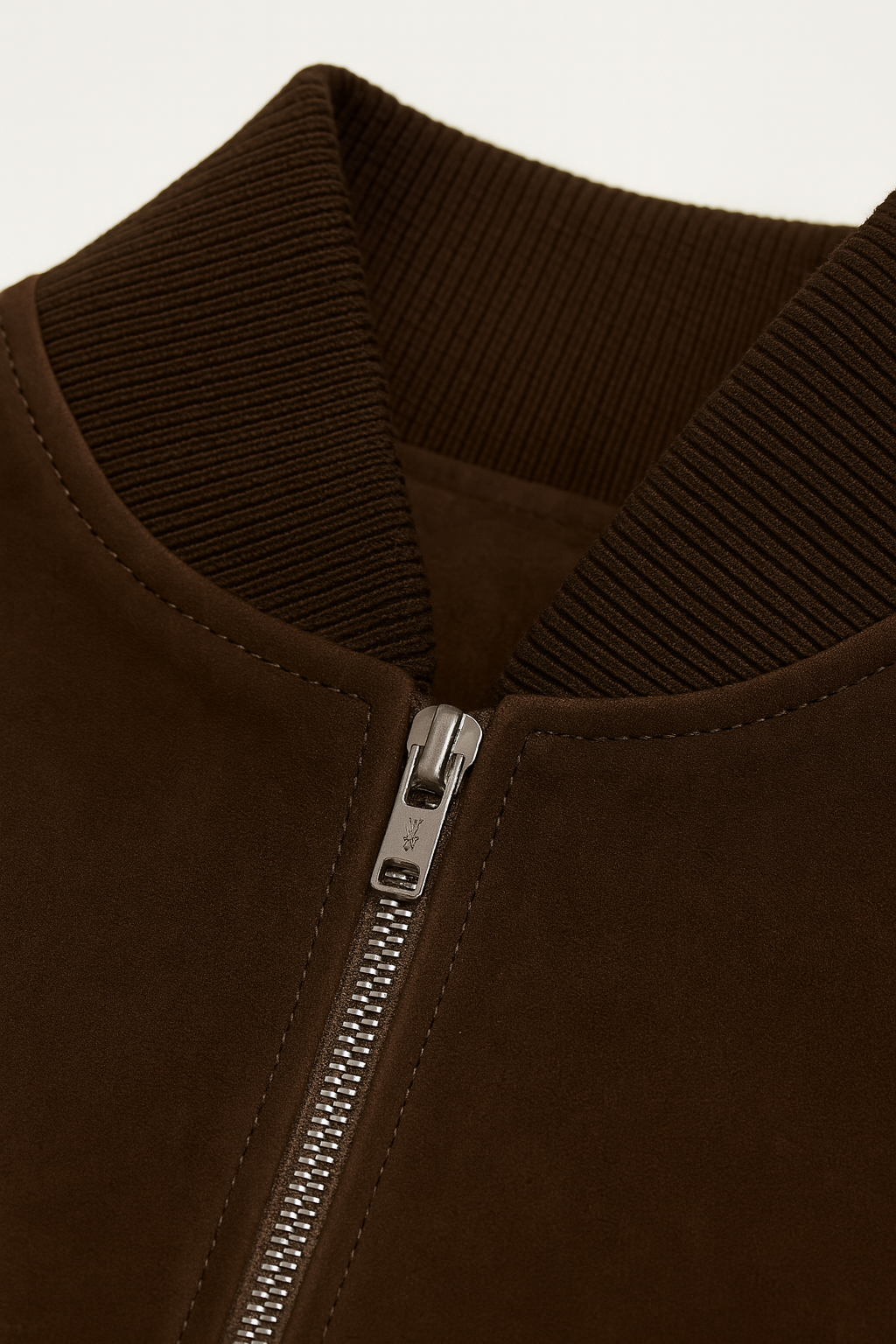 Close-up of a brown jacket with a zipper on a light beige background