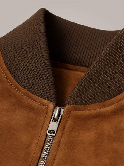 Close-up of a brown suede jacket with a zipper on a neutral background