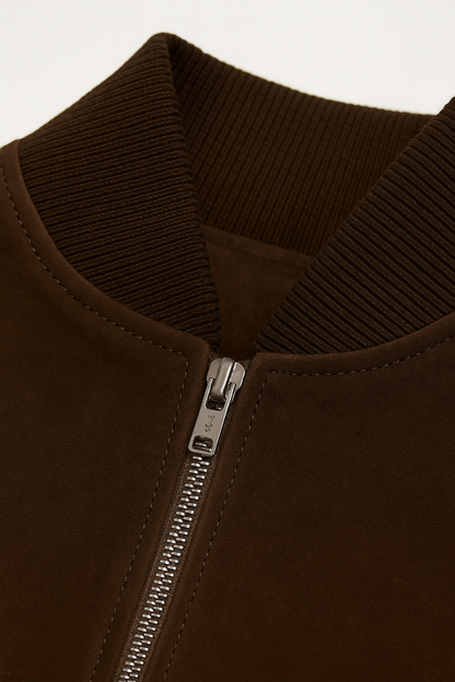 Close-up of a brown jacket with a zipper on a light beige background